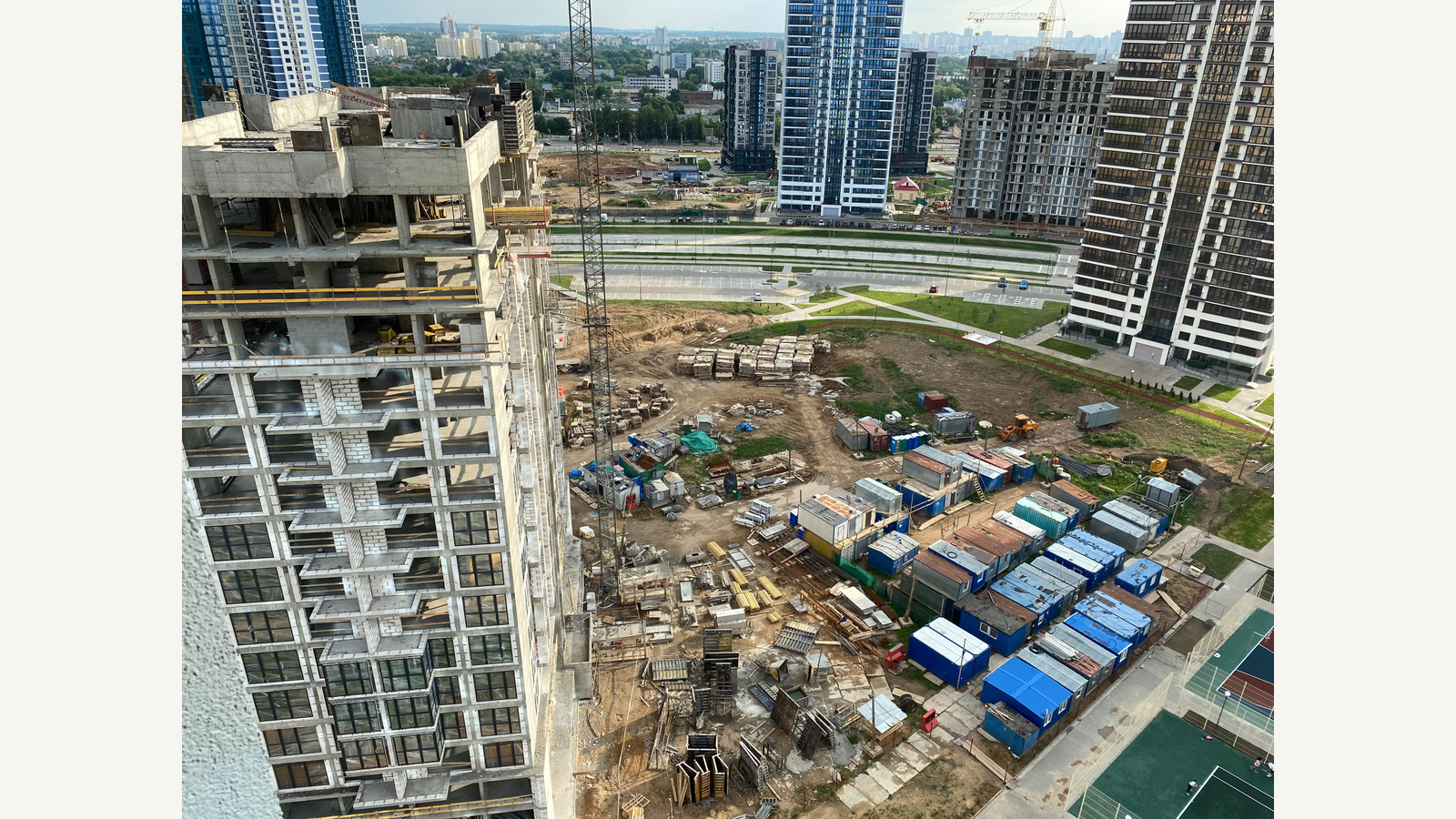 Illustration of a high-rise building under construction with a tower crane and other city buildings.